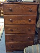 A narrow chest of five drawers.
