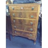 A walnut chest of five drawers.