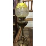 A brass mounted oil lamp with yellow glass shade.
