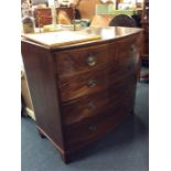 A mahogany bow front chest of drawers on bun feet.