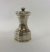 A silver circular pepper grinder with crested armo