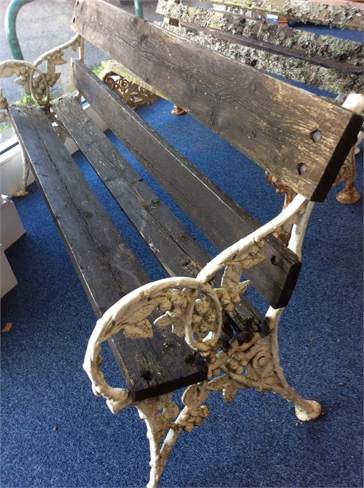 A cast painted garden bench decorated with leaves