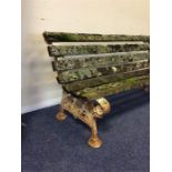 A cast garden bench with scroll decoration and pla