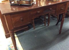 A mahogany three drawer desk on turned and ring su