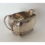 A heavy Art Deco silver cream jug on ball feet with textu