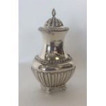 A large half fluted silver caster on ball feet wit