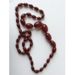 A long graduated string of red amber beads. Approx