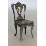 A miniature silver chair with embossed decoration