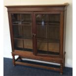 A small oak glazed bookcase with stretcher base an