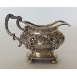 A silver embossed cream jug on ball feet. Birmingh