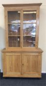 A large pine two part bookcase with glazed doors.