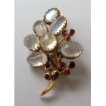 A stylish ruby and moonstone brooch in the form of