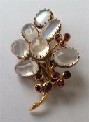 A stylish ruby and moonstone brooch in the form of