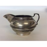 A small circular silver cream jug on pedestal base. Londo