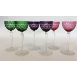 A set of six cut glass coloured wine glasses on ta