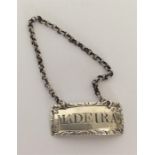 A small rectangular silver Madeira label on suspension ch