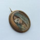 An attractive gold oval miniature of a lady with h