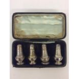 A boxed set of four Edwardian silver peppers with