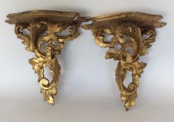 A pair of gilded wall brackets decorated with scro