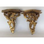 A pair of gilded wall brackets decorated with scro