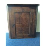 A Georgian oak corner cupboard with panelled front