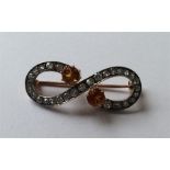 A diamond and topaz brooch of swirl form in two co