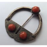 A coral mounted cloak pin engraved with leaves and