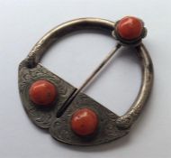 A coral mounted cloak pin engraved with leaves and
