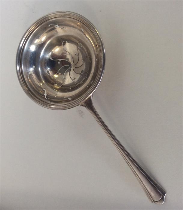 An Art Deco silver tea strainer of circular form.