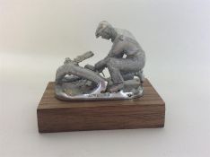 A small silver model of a kneeling gent on wooden