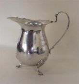 A heavy modern cream jug on reeded feet with silve