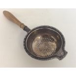 A small Edwardian tea strainer with turned handle.