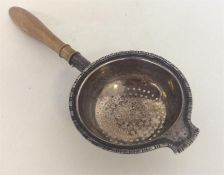 A small Edwardian tea strainer with turned handle.