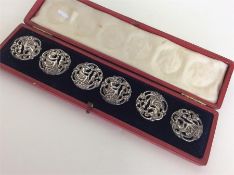 A cased set of six silver embossed buttons decorat