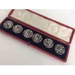 A cased set of six silver embossed buttons decorat