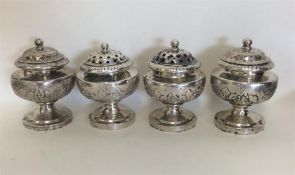 A heavy set of four silver peppers decorated with