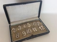 A boxed set of silver menu holders depicting numbe