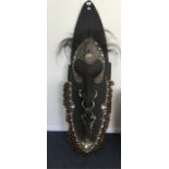 A massive tribal mask heavily decorated with shell