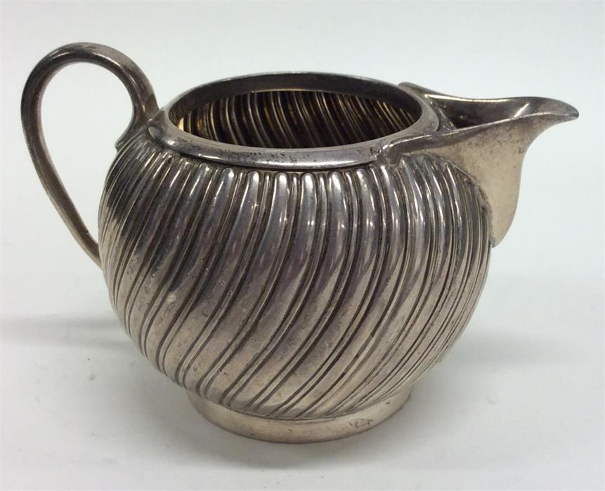 A small silver fluted cream jug on pedestal base.