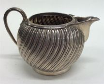 A small silver fluted cream jug on pedestal base.