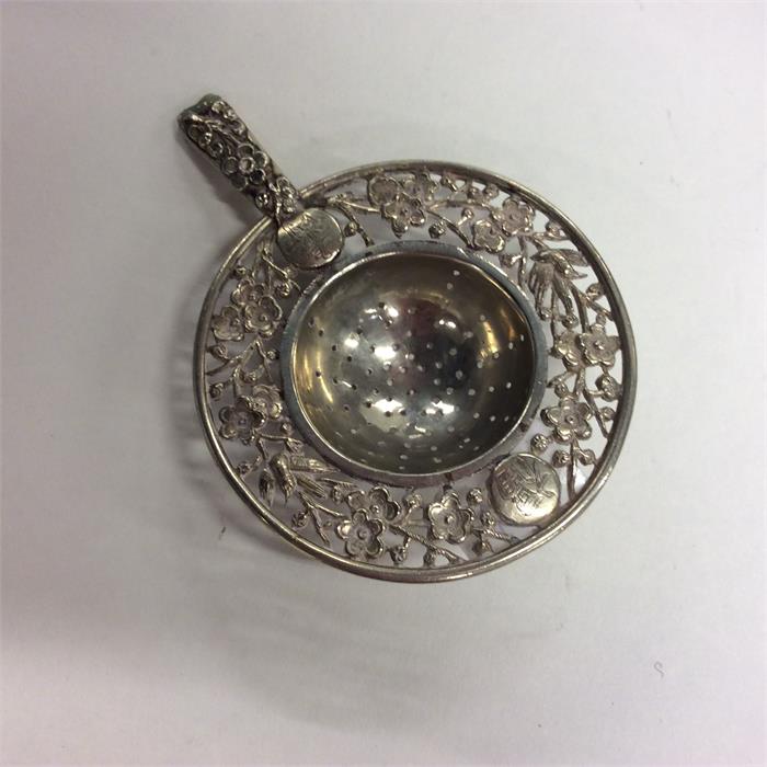 A small Chinese silver tea strainer decorated with