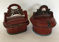 A pair of red lacquered baskets with hinged tops.
