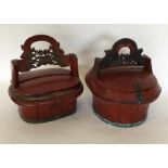 A pair of red lacquered baskets with hinged tops.