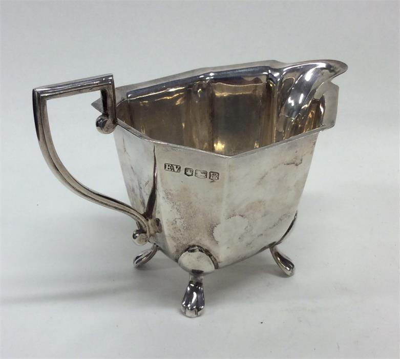 An Art Deco silver cream jug on four pad feet. She