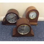 A group of three oak mantle clocks with dome tops.
