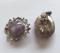 A silver oval locket with buckle decoration togeth