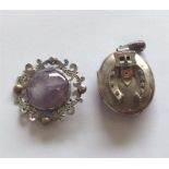 A silver oval locket with buckle decoration togeth