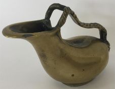 A brass ewer with rope twist handle and masked fig