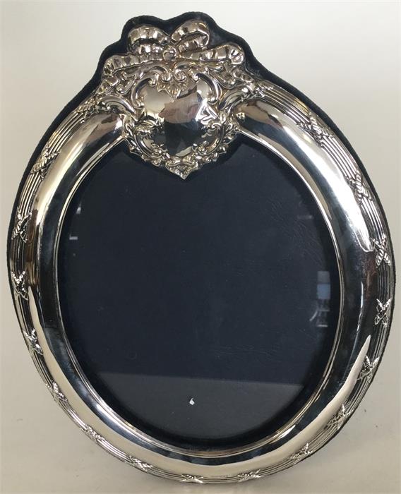 A large modern silver oval picture frame with velv