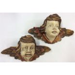 A pair of gilded wall plaques of winged infants wi